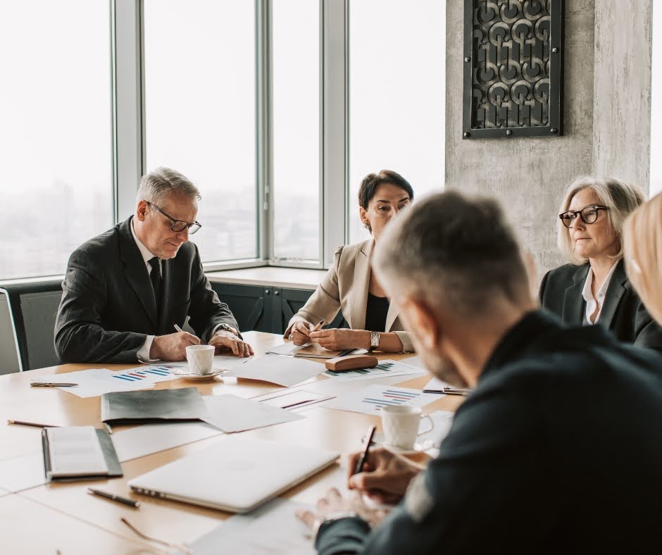 Leadership team analysing business reports and financial data in a modern boardroom setting. The image represents executive decision-making, corporate governance, revenue planning, and enterprise performance optimisation within a strategic management environment.