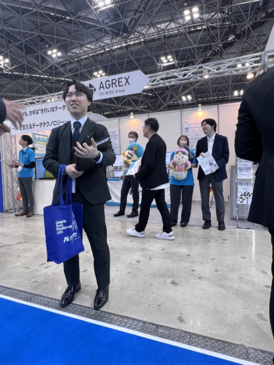 Attendee interacting at Japan IT Week Tokyo 2026 while carrying an Acumen Intelligence tote bag, highlighting brand visibility and booth engagement.