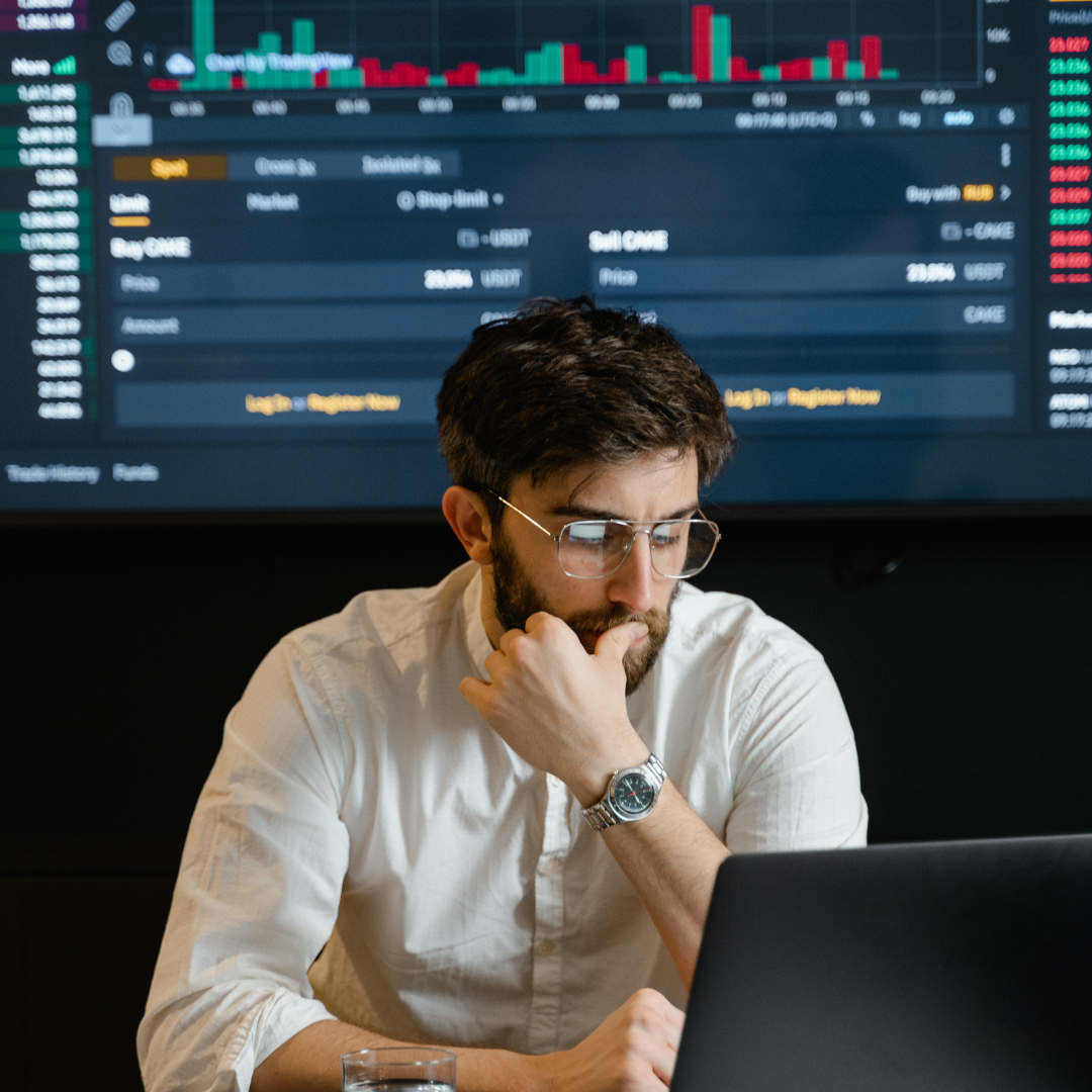 financial analyst in glasses studying crypto and stock market candlestick charts on laptop